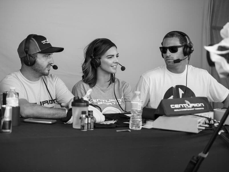 Three competitors sitting at a table with microphones.