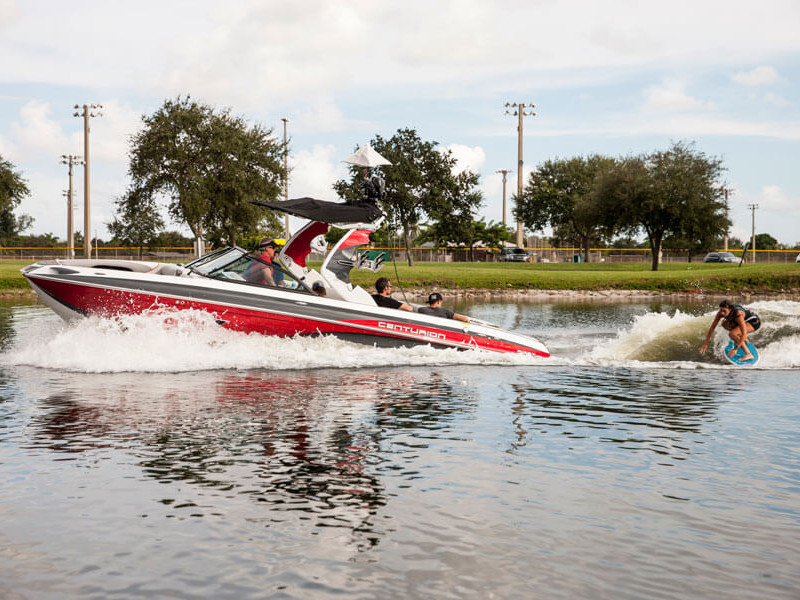 Competitors participate in a wake surfing contest, riding wake boards behind boats.