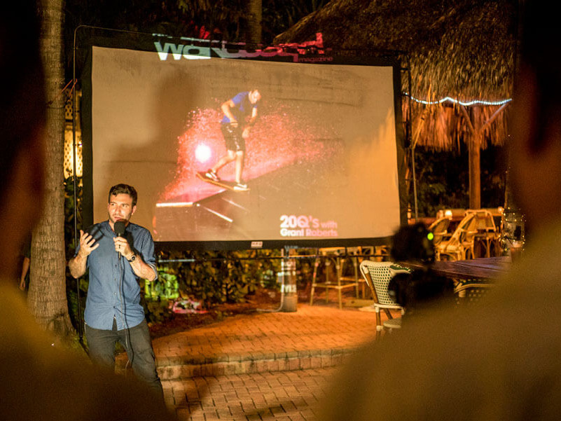 A man giving a presentation about Wake surfing in front of a screen.