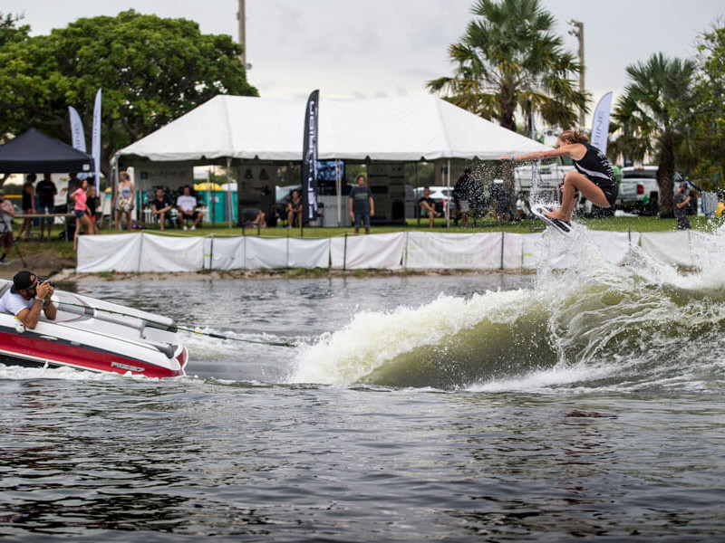 A man is performing a daring trick on a water ski during a competition.