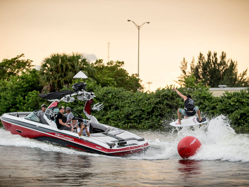 A group of competitors riding a wakeboard on a boat in a contest.