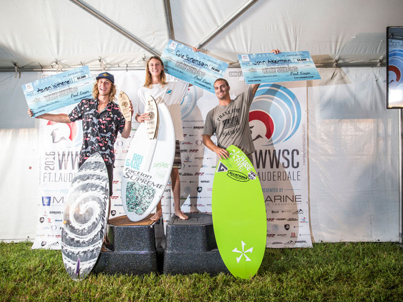 Three surfers standing on top of a podium after a surfing contest.