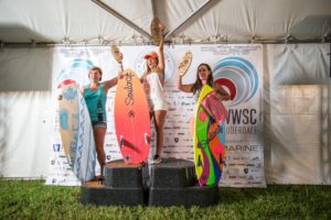 Three surfers standing on top of a podium in a surfing contest.