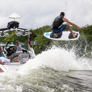 A man is wakeboarding behind a boat, performing impressive tricks and maneuvers.
