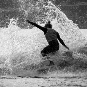 A black and white photo of a surfer riding a wave.