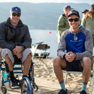 Two surfers in wheelchairs sitting on a beach.