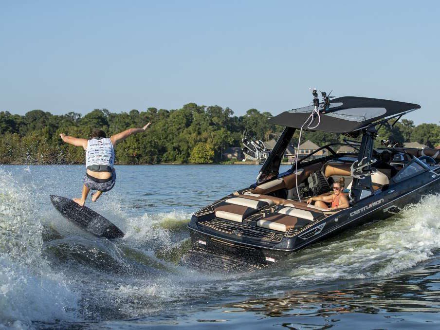 A man is riding a wakeboard and participating in a wake surfing contest.