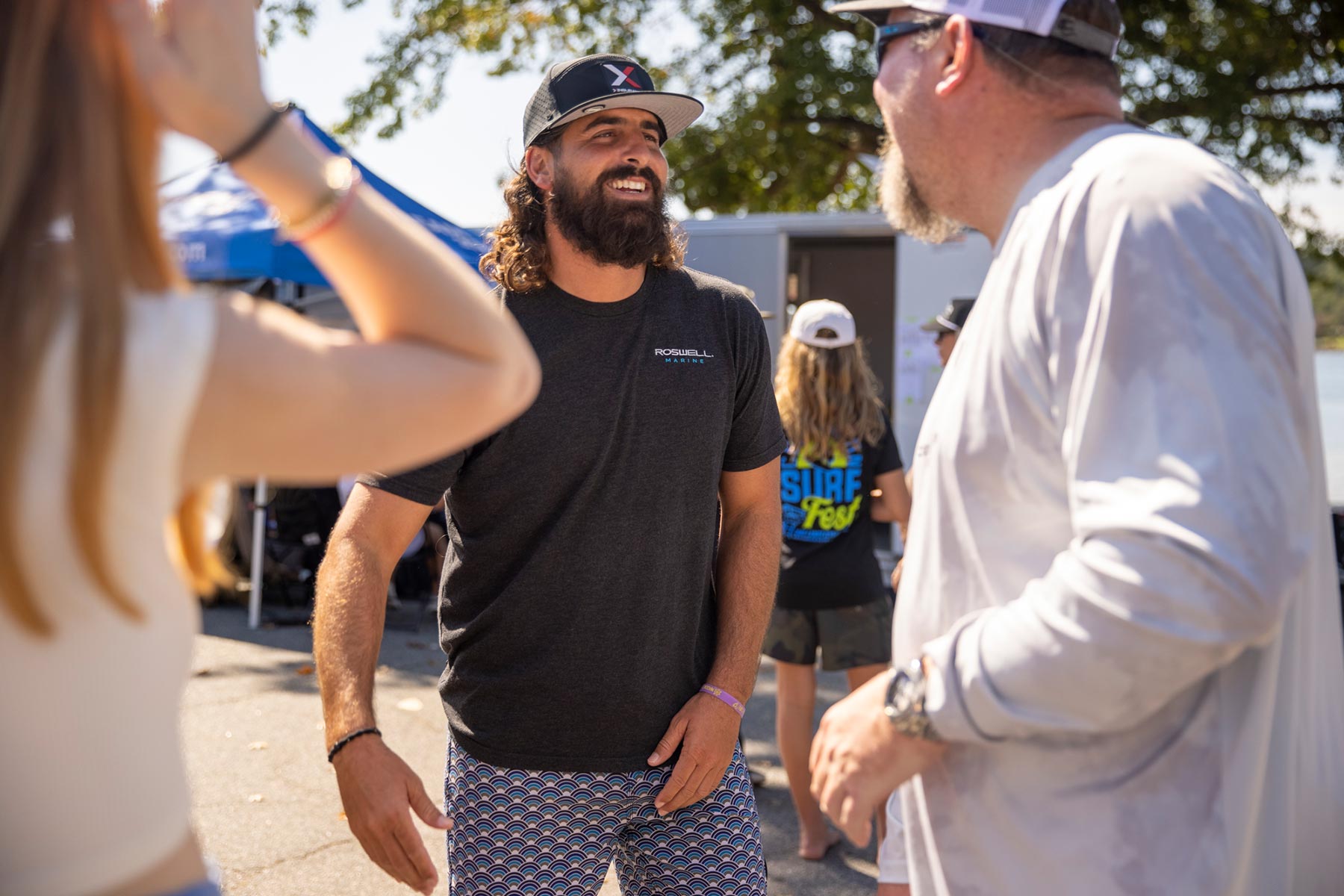 A man with a beard is talking to a group of people about the wake surfing competition.