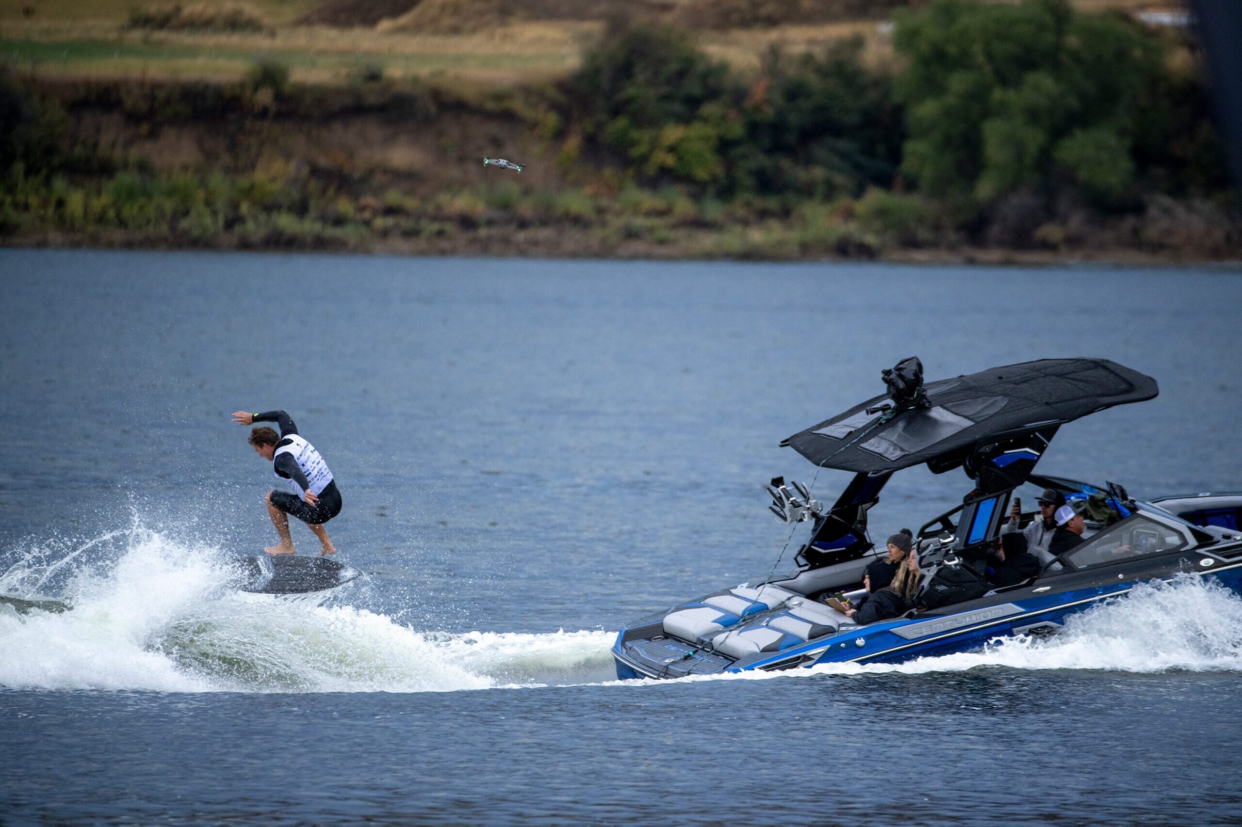 A man is competing in a wakeboarding contest, riding a wake board on a boat.