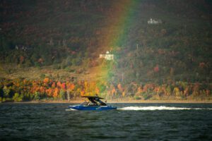 A vibrant rainbow stretches across the sky, captivating Wake surfers and their competitors in a colorful display of natural beauty.