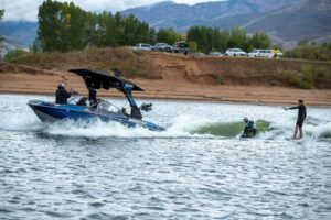 A group of people engaged in a spirited contest of wake surfing aboard a boat in the water.