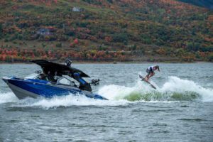A competitor wake surfing on a boat while fans cheer.