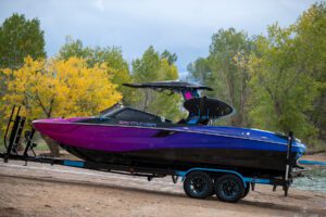 A blue and purple speed boat, perfect for wake surfing competitions, parked on a trailer.