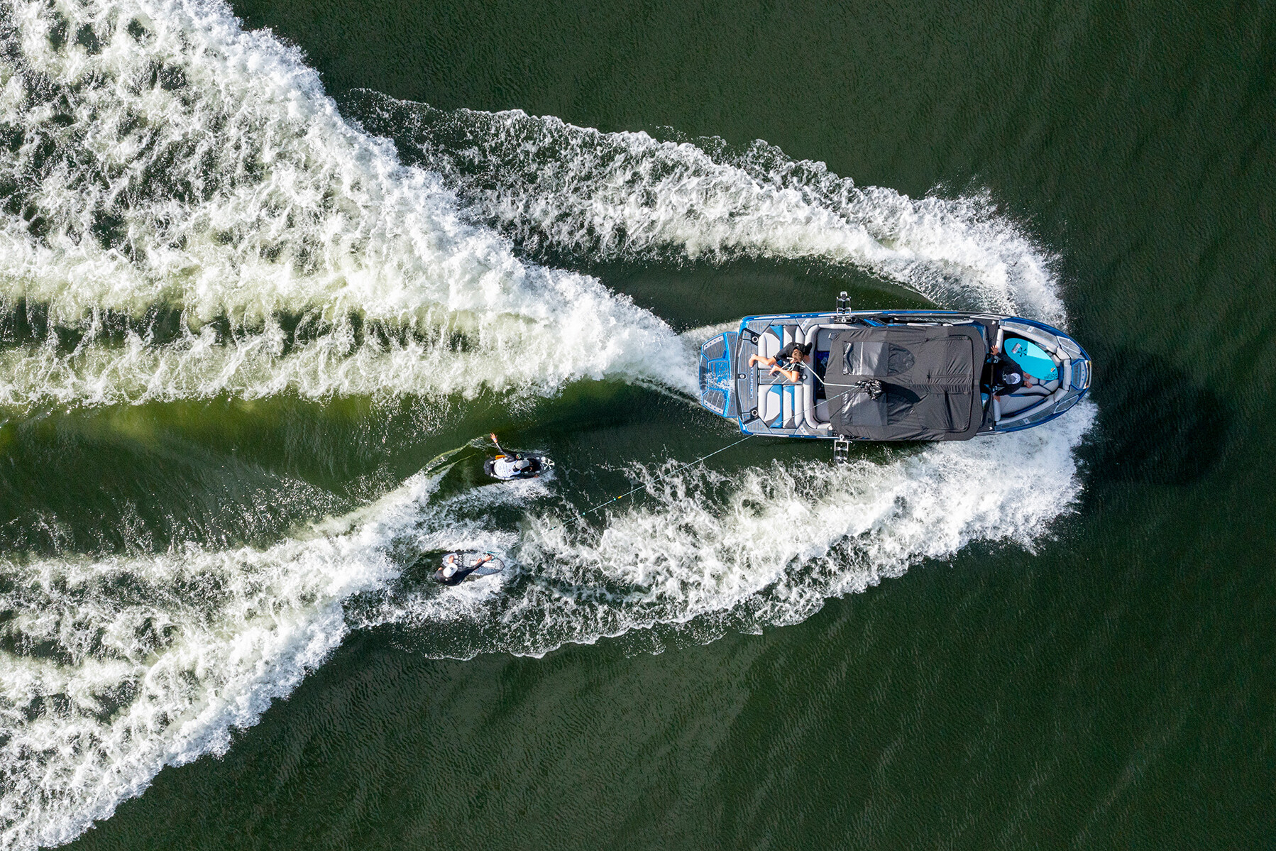 An aerial view of two surfers riding a boat in the water.