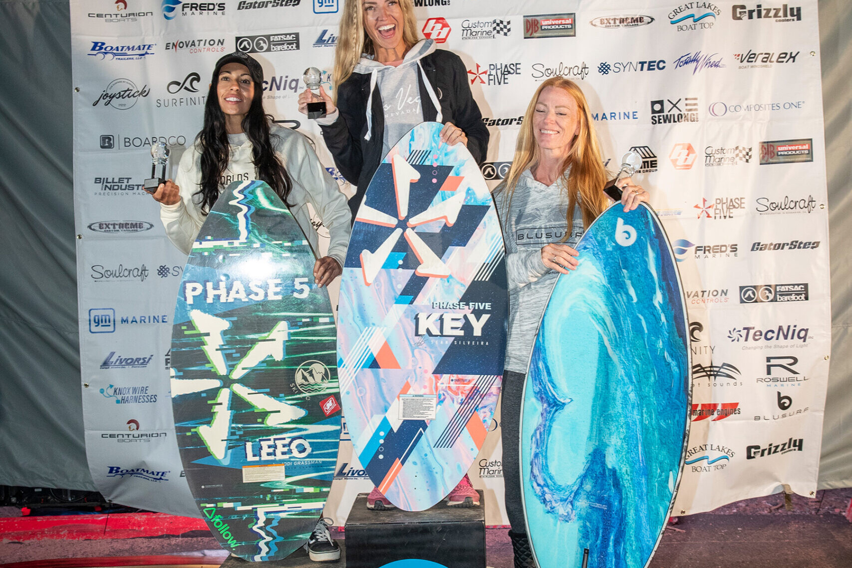 A group of surf competitors posing for a photo with their surfboards.