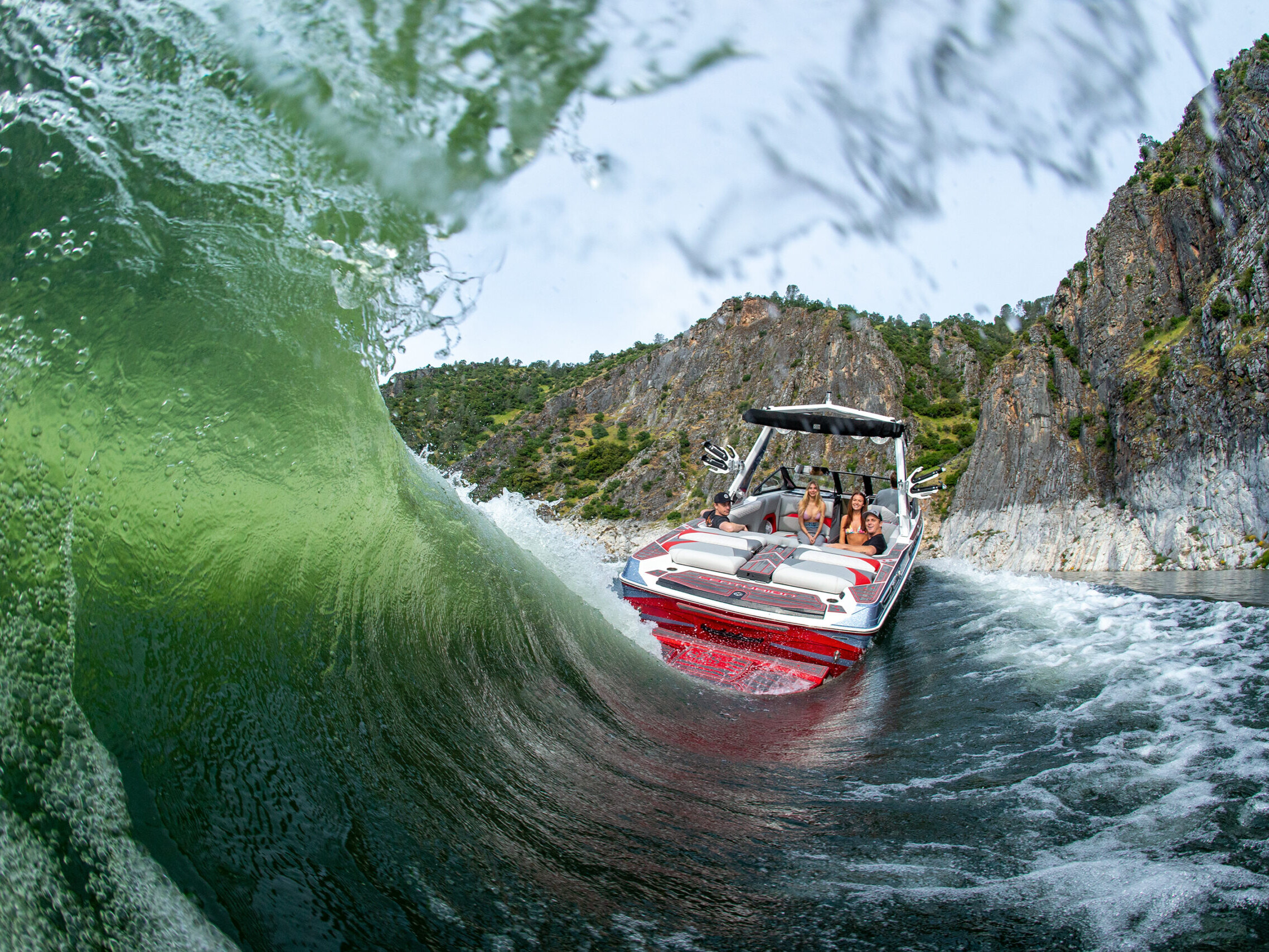 Surfers compete as their boat navigates through a massive wave, thrilling fans.