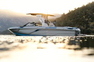The Centurion Ri Series, a boat, gracefully navigates the water with the majestic mountains as its backdrop.