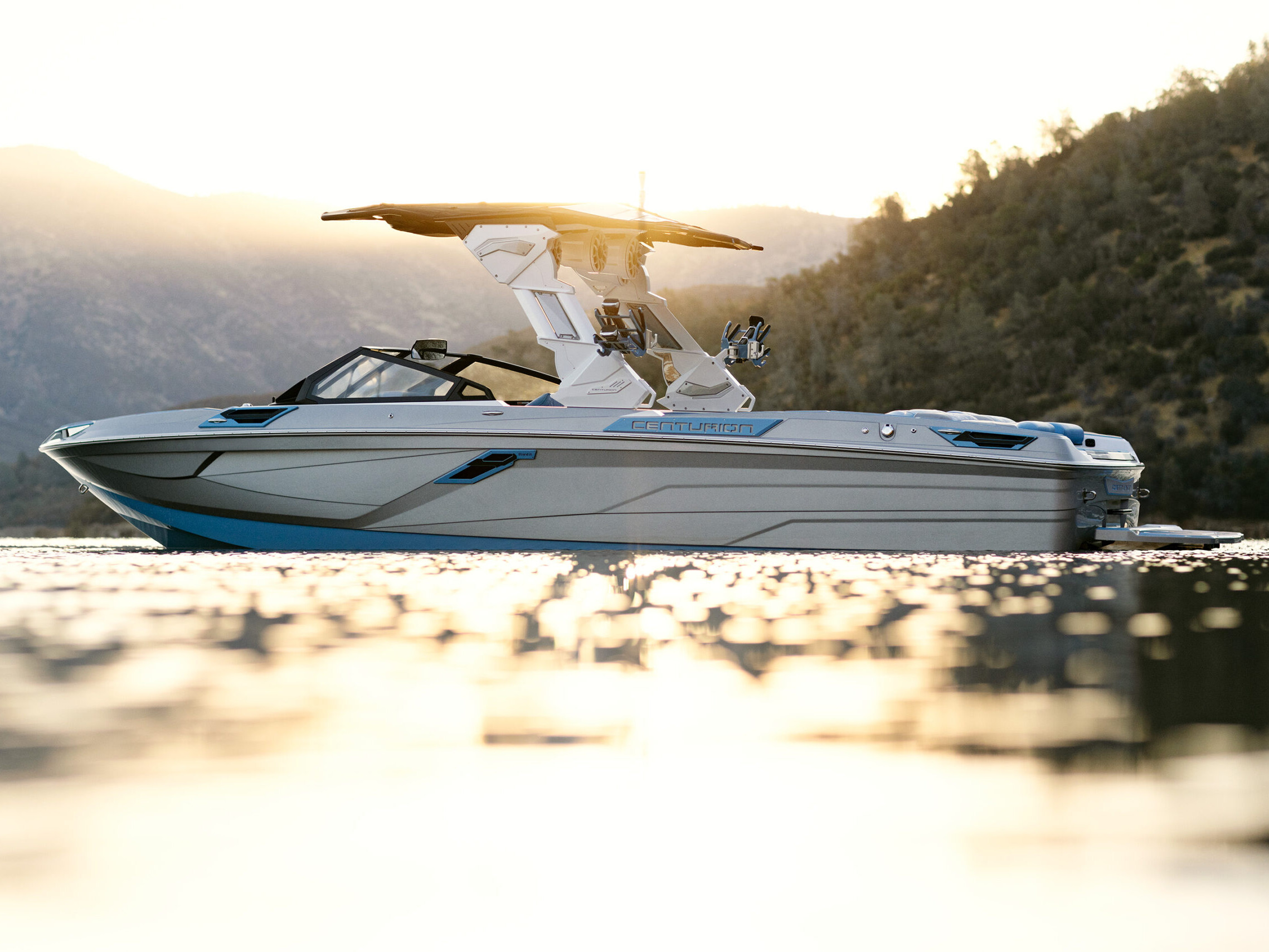 The Centurion Ri Series, a boat, gracefully navigates the water with the majestic mountains as its backdrop.