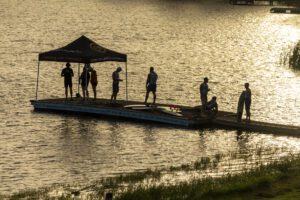 A group of people standing on a dock on water.