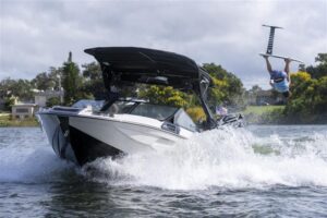 A Centurion Boat speeds through the water, creating waves, while a person on a hydrofoil board is airborne above the surface behind the boat—capturing the thrill of the World Series of Wake Surfing 2026 Tour.