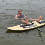 A man wearing a life jacket floats on his back in Lake Conroe next to a paddleboard with his feet resting on it during the S2S Event.