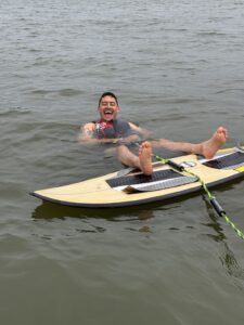 A man wearing a life jacket floats on his back in Lake Conroe next to a paddleboard with his feet resting on it during the S2S Event.