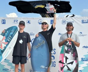 Three men stand on a winners' podium holding wakesurf boards at the World Series of Wakesurfing event, featuring Centurion Boats and Ski Dock, with a branded backdrop behind them.